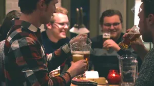 Foto van café/restaurant waar aantal mannen drank, bier, drinken aan een tafel.