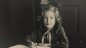 Oude foto, zwart/wit, van een meisje in de klas dat schrijft, ten tijde van de Tweede Wereldoorlog.