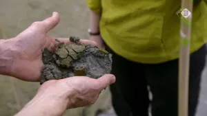 Foto van twee handen die een klomp zand, modder, klei vasthouden om te bekijken, onderzoeken.