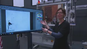 Foto van een groot computerscherm met tekenprogramma waarbij presentator staat.