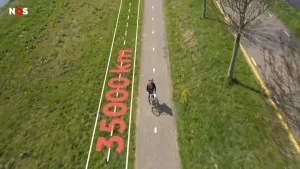 Foto van een fietser op een fietspad van bovenaf gezien met gras erlangs, langs het fietspad is de tekst "35000 km" afgebeeld.