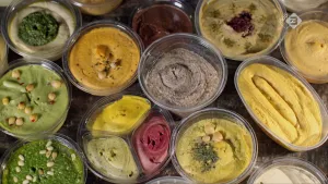 Foto van ronde glazen bakjes met daarin verschillende soorten hummus, van bovenaf gezien.