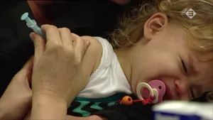 Foto van heel jong meisje, peuter/baby, die in haar arm wordt ingeënt.