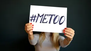 Foto van vrouw die voor haar hoofd een wit bord vasthoudt met erop de tekst "#METOO".