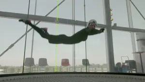 Foto van man met helm op die zweeft in een indoor skydive ruimte.