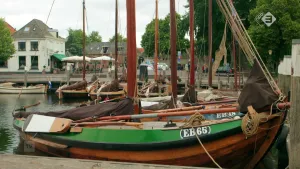 Foto van aantal oudere zeilschepen die liggen in kleine haven van een stadje/dorp.
