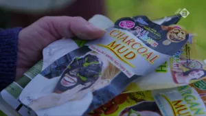 Foto van verpakkingen van kleimaskers vastgehouden door een hand.