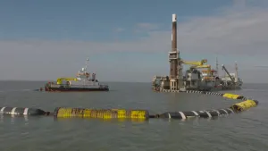 Foto van twee boten op het water, één ervan met grote machine erop die zuigt slib, zand.