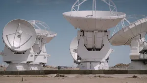 Foto van aantal grote radiotelescopen die staan op woenstijnachtig terrein.
