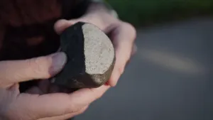 Foto van twee handen die een vrij grote meteoriet vasthouden.