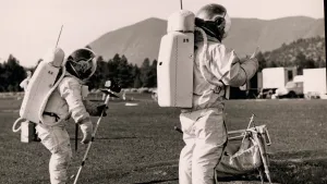 Foto, zwart/wit, van twee astronauten die op een grasveld in de natuur op aarde oefeningen doen.