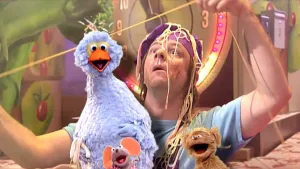 Foto van Sesamstraat met presentator, Pino, Tommie en Ieniemienie, ze zitten onder de spaghetti.