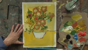 Foto van een schilderij door iemand nagemaakt van de Zonnebloemen van Van Gogh, erbij een palet met verf erop.