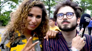 Foto van man en vrouw op festivalterrein, de man houdt een microfoon vast.