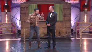 Foto van de studio van Snugger waarop de presentator op het podium staat in gesprek met man die een cowboyhoed vasthoudt.