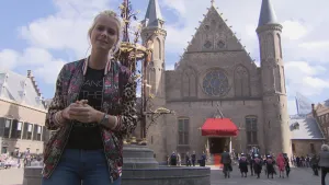 Foto van presentator op het Binnenhof met de gebouwen ervan in beeld.