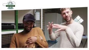 Foto van twee mannen die staan in een kamer, de ene houdt een bruin konijn vast.