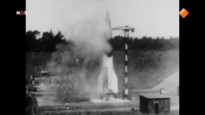 Foto van NOS-Journaal waarop een grote oude zwart/wit foto te zien is van een kleinere raket die gelanceerd wordt.
