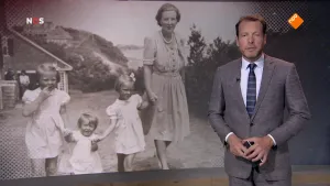 Foto van het NOS-Journaal met de nieuwslezer die staat voor een grote zwart/wit foto met moeder met kinderen die buiten staan ten tijde van de Bevrijding.