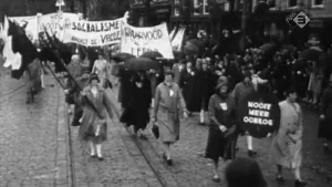 Oud foto, zwart/wit, van een demonstratie, betoging, op straat, mensen met spandoeken.