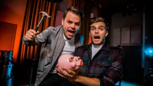 Foto van twee mannen die een roze spaarvarken vasthouden, de ene man houdt hamer vast om deze kapot te slaan.