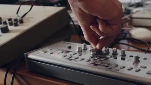 Foto van geluidsapparatuur met knoppenbord, een hand in beeld die één van de knopjes bedient.
