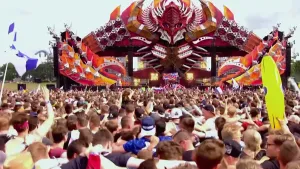 Foto van festival, Defcon, vele mensen op het veld en groot uitbundig versierd podium.