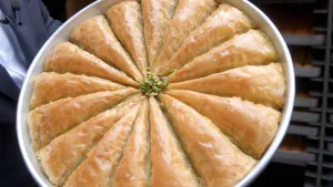 Foto van een ronde bakvorm met daarin in het rond allemaal stukken baklava.