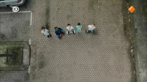 Foto van rij met vijf kinderen die staat op straat, van bovenaf gezien.