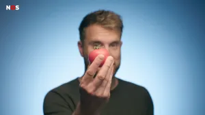 Foto van presentator, je ziet zijn hoofd, die voor zich in zijn hand een tomaat vasthoudt.