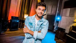 Foto van presentator, Buddy Vedder, in studioruimte met boxen, geluidsapparatuur.