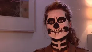 Foto van een vrouw die eng, spookachtig, zwart/wit is geschminkt voor Halloween, je ziet alleen haar gezicht.