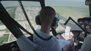 Foto van piloot die in een helikopter zit die vliegt boven het land.