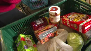 Foto van voedselproducten zoals thee en potjes met broodbeleg in een krat bij de voedselbank.