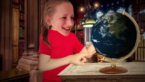 Foto van een jong meisje dat staat bij een globe/wereldbol en ernaar kijkt en wijst.