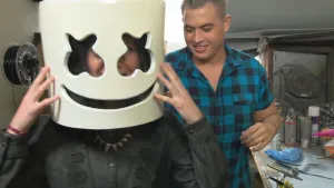 Foto van man, ernaast een vrouw die een soort groot masker vasthoudt voor haar gezicht.