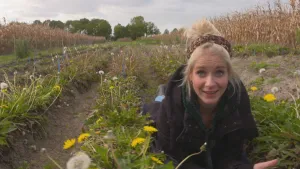 Foto van presentator die op haar buik ligt op een pad met vele wilde bloemen.