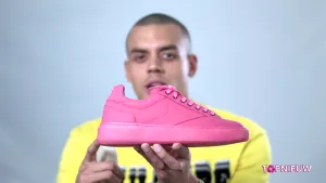 Foto van presentator die een roze schoen vasthoudt.