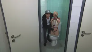 Foto van een WC waarin een man staat bij model met organen van een mens, de buik en het hoofd, neergezet op de WC.