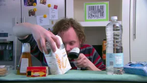 Foto van presentator die met een scanner een pak met bloem scant aan een tafel in een kamer.