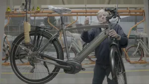 Foto van man die bezig is aan een E-bike, elektrische fiets, in fabriekshal.