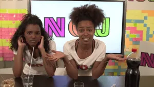 Foto van twee vrouwen aan de desk in de studio, fles Cola staat erop en paar glazen, een microfoon.