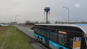 Foto van een bus, waterstofbus, die bij een halte staat langs weg buiten de stad.