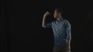 Foto van een man, heel donker, in donkere ruimte, die een dartpijltje weggooit.