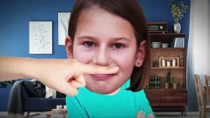 Foto van  het gezicht van een meisje, met de vinger van iemand die tegen haar neus aan zit.