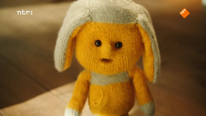 Foto van Dropje, een stoffen pop, die op de grond staat.