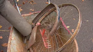 Foto van oude ijzeren voorwerpen die roesten die op straat liggen, zoals oud fietswiel en hark.