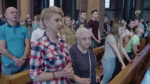 Foto van mensen en kinderen die staan bij kerkbanken in moderne kerkzaal.