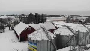 Foto van een kleine fabriek in de sneeuw met erbij drie ronde silo's.