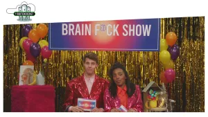 Foto van studio met man en vrouw aan tafel, erboven de tekst "brain fuck show".